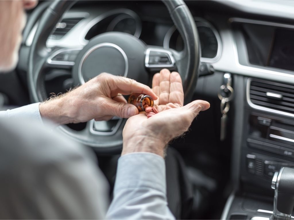 man taking pills in a car