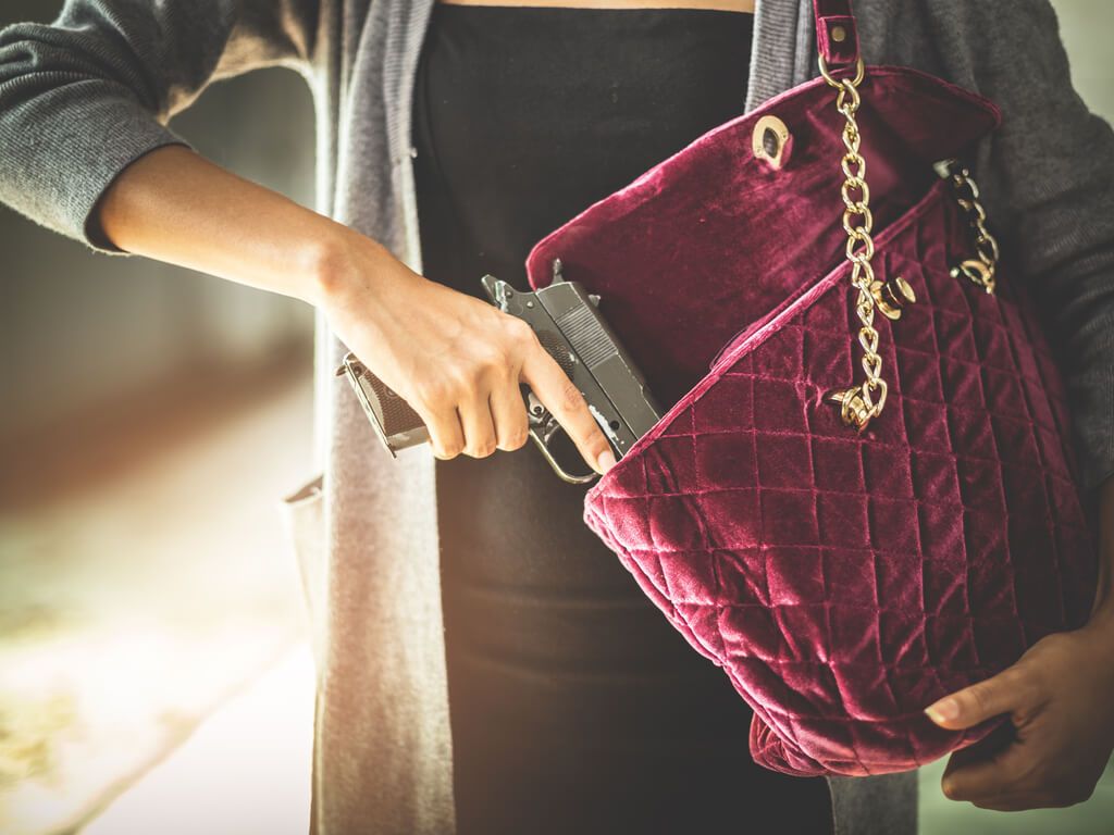 woman pulling a gun out from her purse