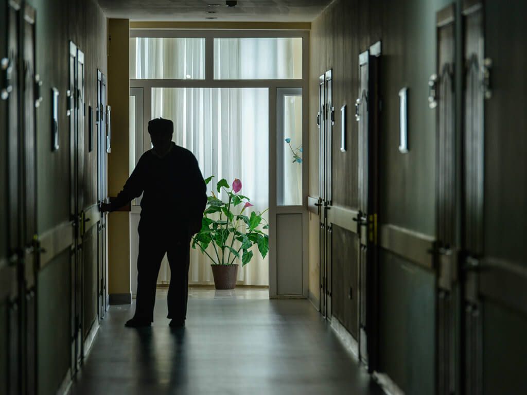 elderly man walking in a dark nursing home hallway