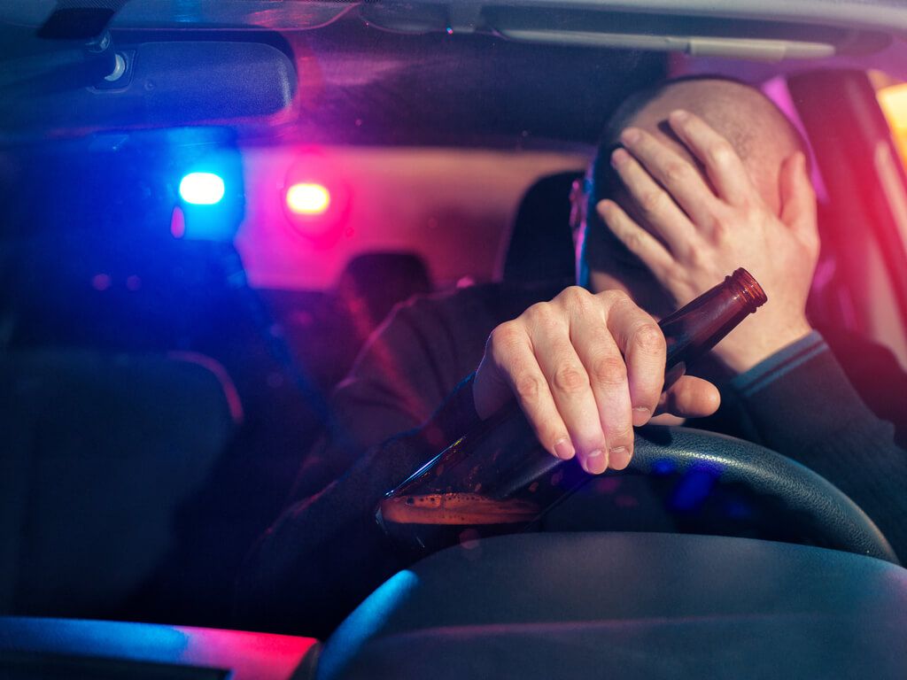 drunk driver holding beer bottle being pulled over by police