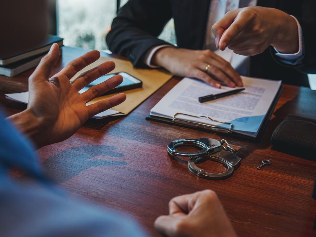 a legal meeting between two people with handcuffs on the desk